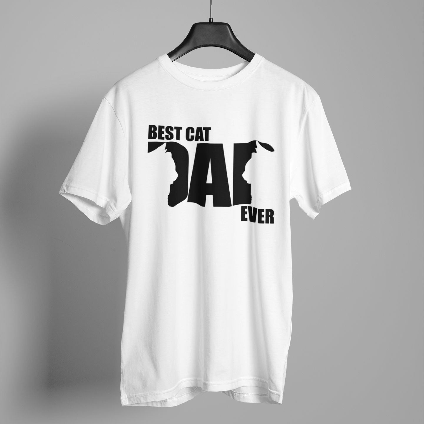 White t-shirt with 'BEST CAT DAD EVER' text on a hanger against a gray background