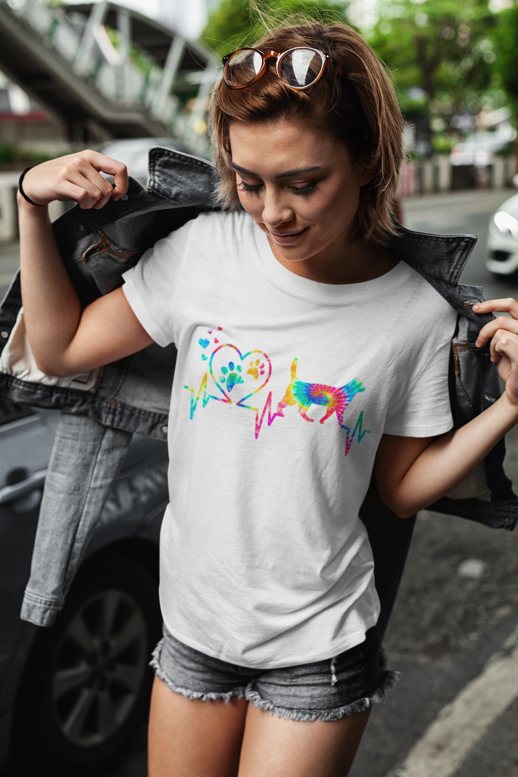 Woman wearing a white t-shirt with colorful dog design outdoors.