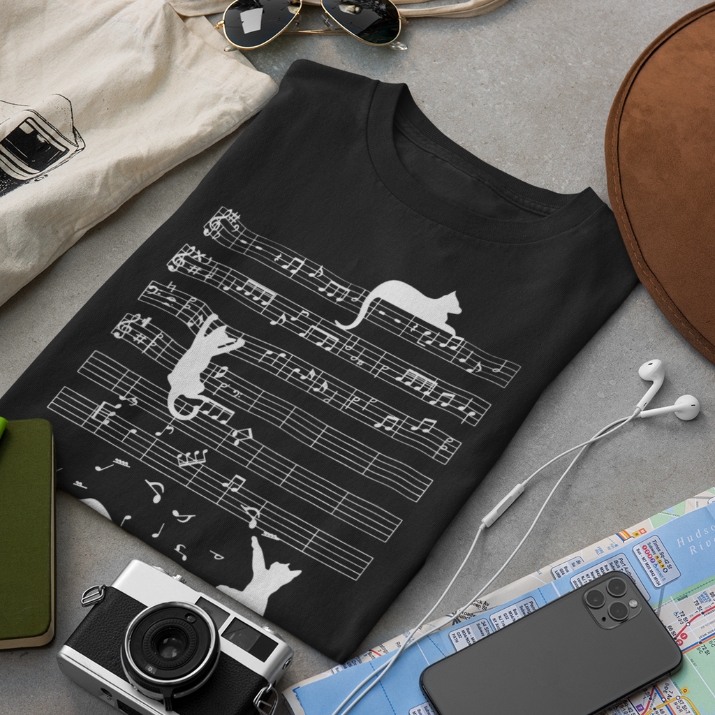 Black t-shirt with musical notes and cat design on a gray surface with accessories.